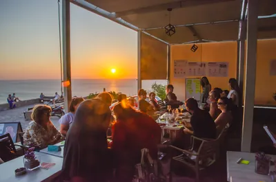 A participatory workshop at tables overlooking the sea at sunset.